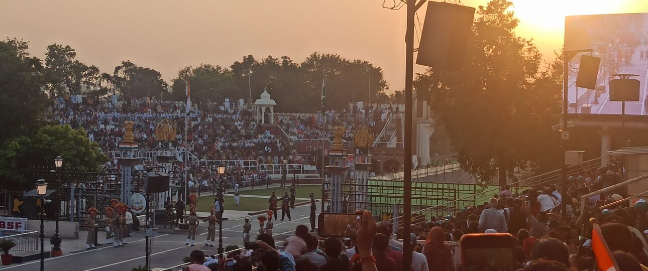 Indian and Pakistani soldiers performing the Wagah Border flag-lowering ceremony at sunset, with crowds cheering in the background."