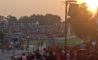 Indian and Pakistani soldiers performing the Wagah Border flag-lowering ceremony at sunset, with crowds cheering in the background."