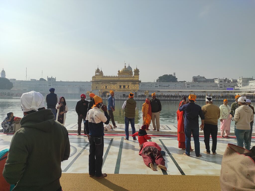 Harmandir Sahib Golden Temple Amritsar illuminated with pilgrims walking around the Sarovar