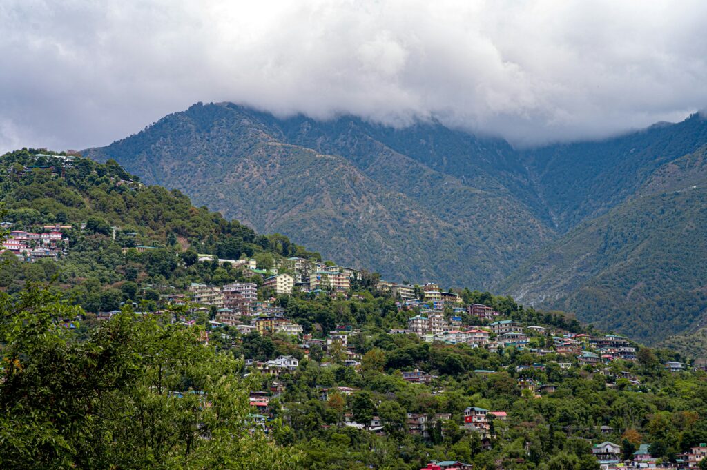 Dharamshala Himachal Pradesh on a cloudy day with misty mountains, lush green hills and dramatic monsoon sky