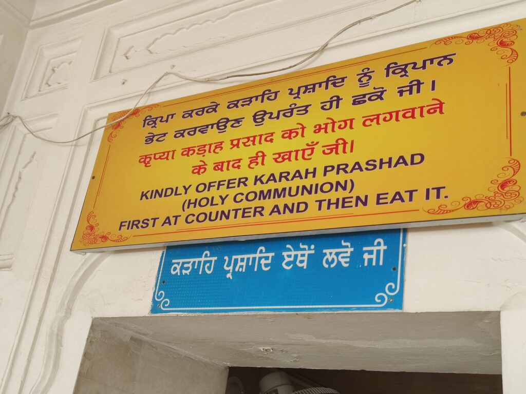 Devotees receiving Karah Prashad at the sacred distribution area inside a gurdwara after offering prayers.