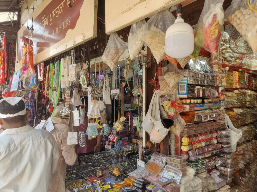 Bustling bazaar outside the Golden Temple in Amritsar with shops selling traditional Punjabi souvenirs, religious items, colorful textiles, and local street food.